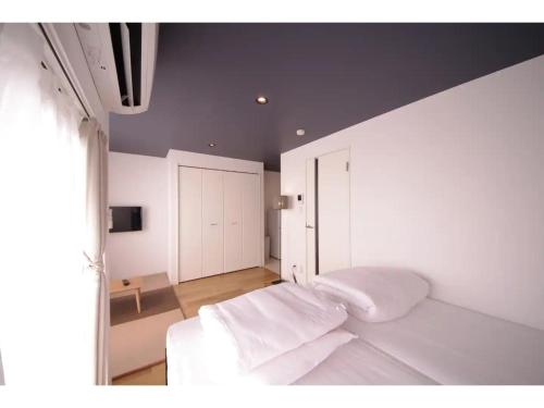a bedroom with a bed with white sheets and a window at HOTEL APT SESELA - Vacation STAY 12880 in Kanazawa