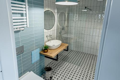 La salle de bains est pourvue de carrelage bleu, d'un lavabo et d'un miroir. dans l'établissement Apartament Wschodni, à Supraśl