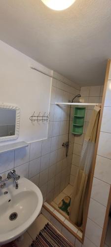 La salle de bains est pourvue d'un lavabo et d'une douche. dans l'établissement Dom Bursztynek - domek (sad), à Junoszyno