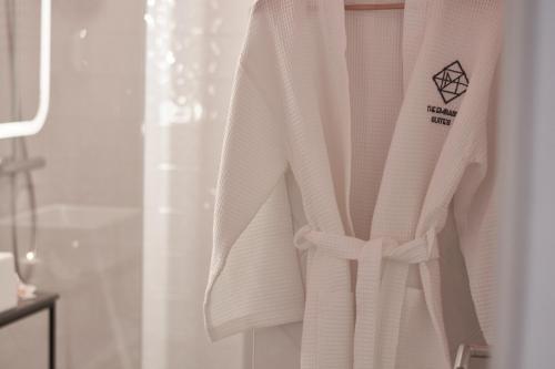 a white robe is hanging in a bathroom at The Embassy Suites in Sofia