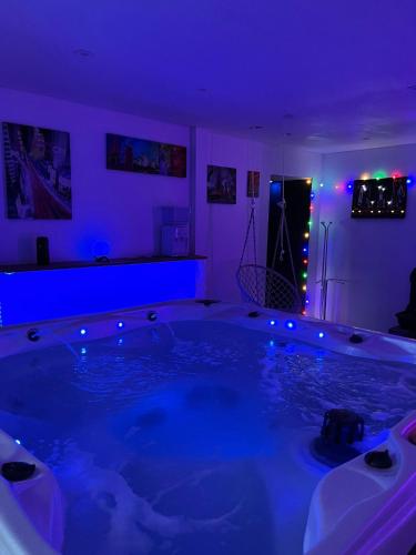 een groot bad in een kamer met paarse verlichting bij Suite Saona in Feuquières