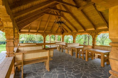 a wooden pavilion with benches and tables in it at Pensiunea Coronita in Vişeu de Sus
