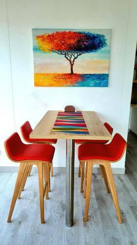 a table with two red chairs and a painting of a tree at Toscana LOFT - Apartasuites in Bogotá