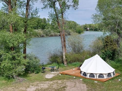 a white tent in the grass next to a lake at Snake River Glamping in Irwin
