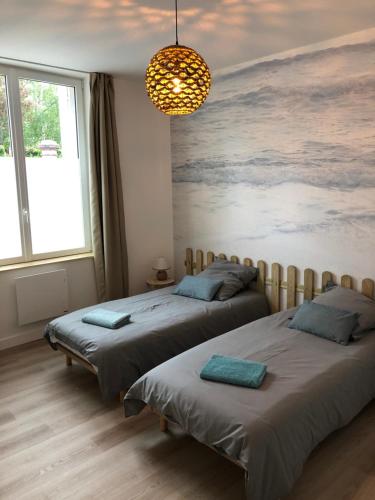 - 2 lits dans une chambre avec un tableau mural dans l'établissement L'Air de la Mer, 2 chambres, 50m plage, parking, à Houlgate
