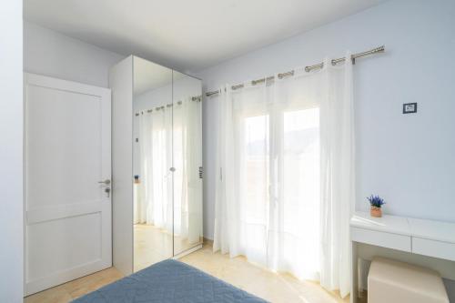 a bedroom with white curtains and a mirror at Blue Coast House in Goúdhouros
