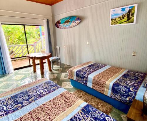 a room with two beds and a table and a window at Kahina Lodge in Hanga Roa