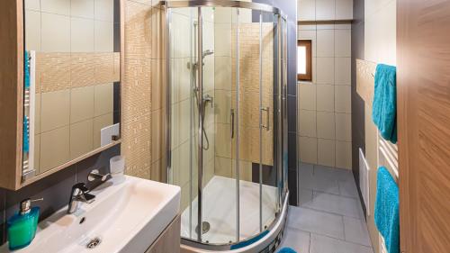 y baño con ducha acristalada y lavamanos. en Apartman Valnela en Veľká Lomnica