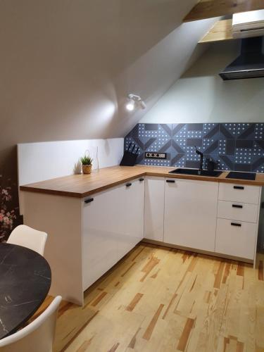 a kitchen with white cabinets and a wooden floor at KK Apartment in Ventspils