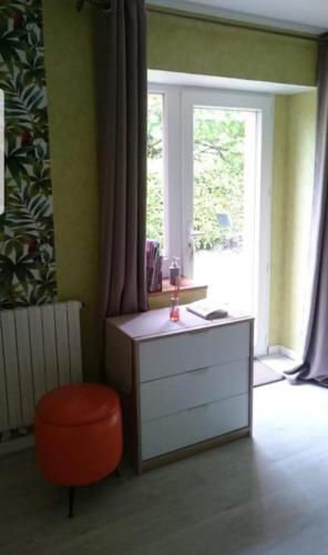 Cette chambre dispose d'une commode, d'un tabouret rouge et d'une fenêtre. dans l'établissement Amour Aquitaine, à Cambes