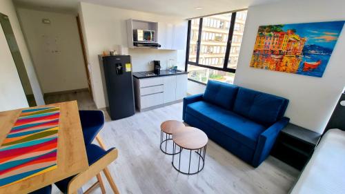 a living room with a blue couch and a kitchen at Toscana LOFT - Apartasuites in Bogotá