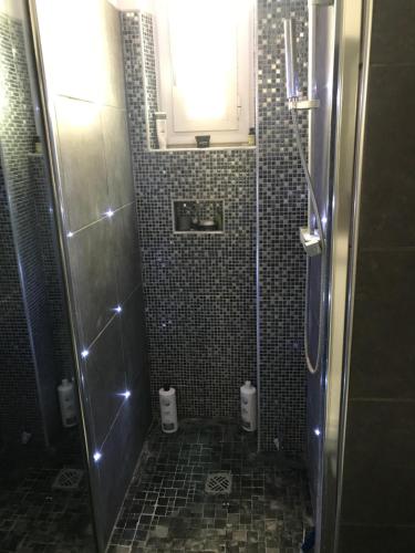 La salle de bains est pourvue d'une douche, de carrelage et d'une fenêtre. dans l'établissement Superbe appartement proche de la butte Montmartre, à Paris