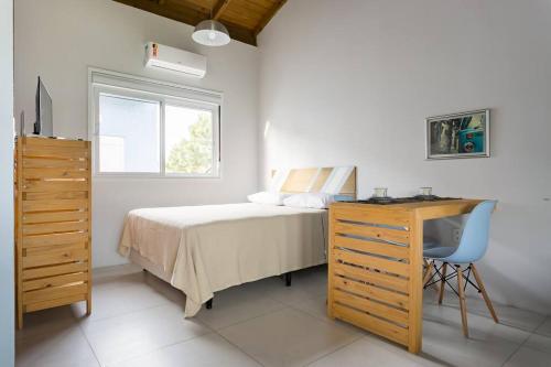 a bedroom with a bed and a desk and a window at Pousada Caminho Nômade in Imbituba