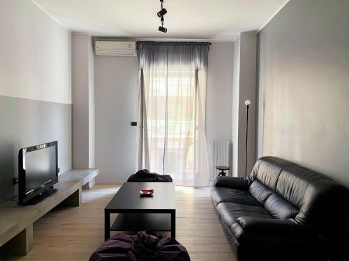 a living room with a black leather couch and a tv at duo apartment in Salerno