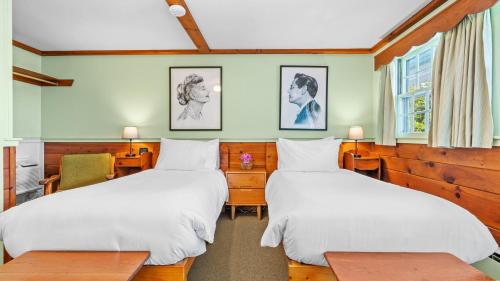 twee bedden in een kamer met twee tafels bij Mid-Town Motel in Boothbay Harbor