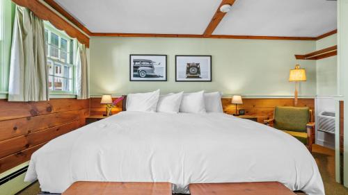 a bedroom with a large white bed and two windows at Mid-Town Motel in Boothbay Harbor