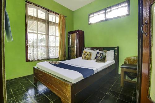 OYO Homes 91155 Desa Wisata Selamanik Ciamis في Buniseuri: غرفة نوم بسرير في غرفة خضراء
