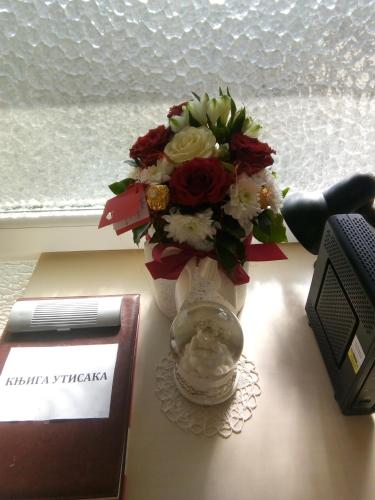 a vase with a bouquet of flowers on a desk at Apartment Vila MM Srce in Vrdnik