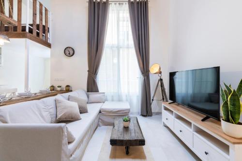 a living room with a white couch and a flat screen tv at 248 Boutique Studios, Sliema in Sliema