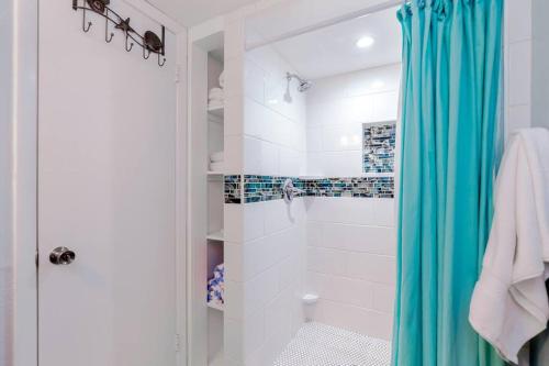 a bathroom with a shower with a blue shower curtain at Updated WATERFRONT, pool, tiki bar, boat ramp, etc in Marathon