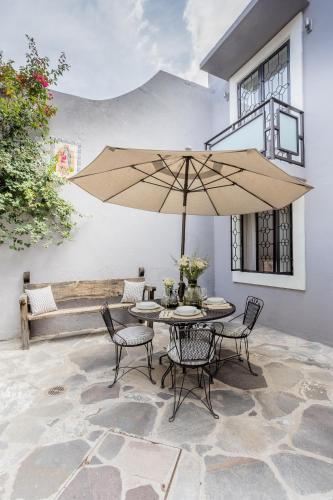 a patio with a table and chairs and an umbrella at Casa Recreo King Suite Apartments in Centro, San Miguel de Allende in San Miguel de Allende