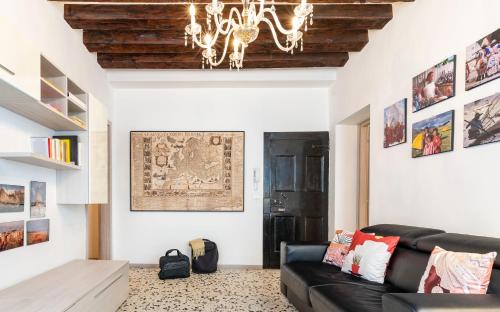 een woonkamer met een zwarte bank en een kroonluchter bij Ponte Squero Flat M0270423226 in Venetië