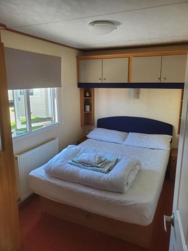 a bedroom with a large bed with white sheets at 92 Barmouth Bay Holiday Park in Llanddwywe