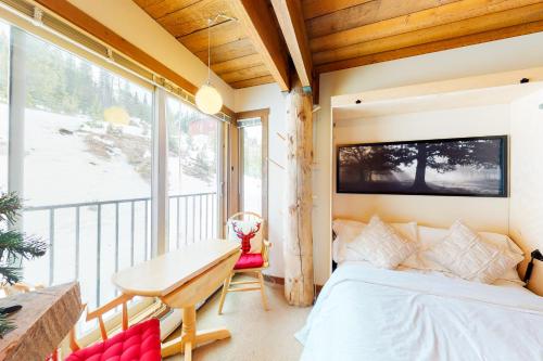 a bedroom with a bed and a desk and a window at Moguls 813 in Big White