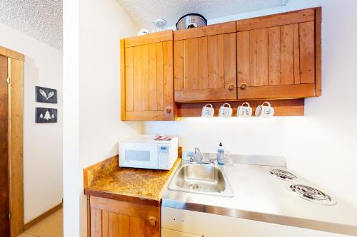 uma cozinha com um lavatório e um micro-ondas em Moguls 813 em Big White
