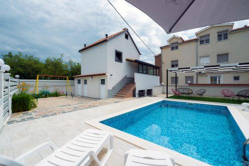 una piscina con 2 sillas y una casa en Luxury with gallery, heated pool only for you-KLIS CRO, en Klis