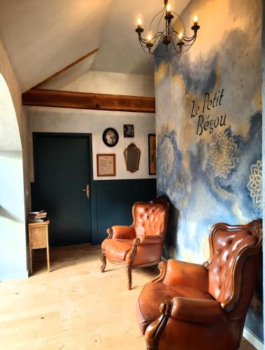 a living room with two leather chairs and a painting at Le Petit Bégou in Saint-Auban-dʼOze