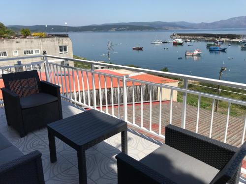 a balcony with chairs and a table and a view of a harbor at Apartamento vista al Puerto de Finisterre in Fisterra