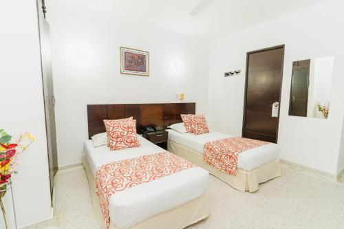 two beds in a room with white walls at Hotel Las Molas in Apartadó