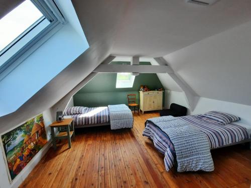 a attic bedroom with two beds and a window at GITE CHEZ BERTHE in Pontfarcy
