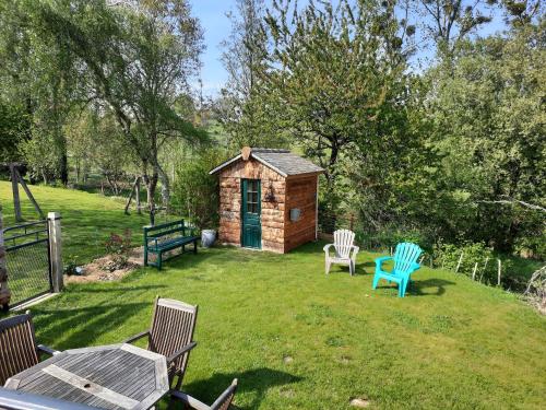 a small cabin in a yard with two chairs at GITE CHEZ BERTHE in Pontfarcy
