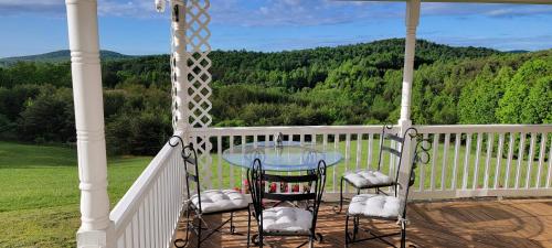 eine Veranda mit einem Glastisch und 2 Stühlen in der Unterkunft Mountain Retreat house to Relax and Enjoy in Lenoir