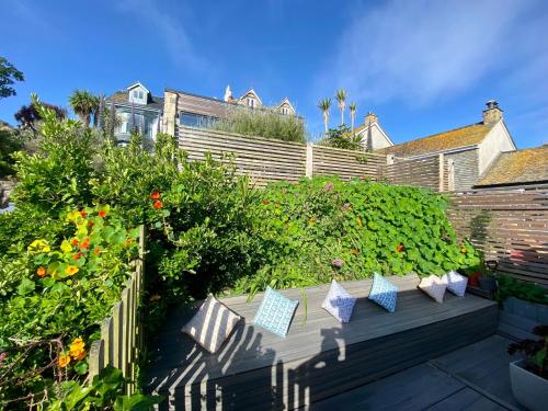 a garden with colorful pillows on a wooden deck at 3 Bedroom Cottage minutes walk from town, harbour & Beaches. in St Ives