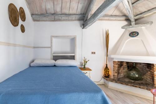 a bedroom with a blue bed and a fireplace at Pefkias Tiny Cottage in Skopelos Town