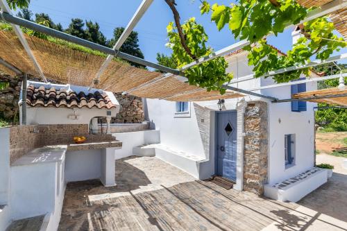 a courtyard in a house with white walls and a blue door at Pefkias Tiny Cottage in Skopelos Town