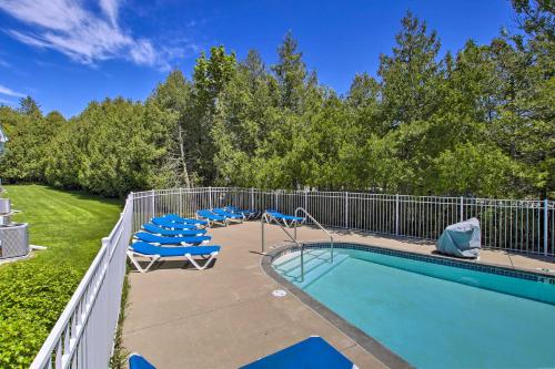 a swimming pool with blue chairs and a fence at Door County Getaway - Walk to State Park! in Fish Creek