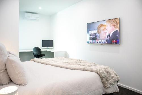 a bedroom with a bed and a tv on the wall at Soho 1A in Geelong