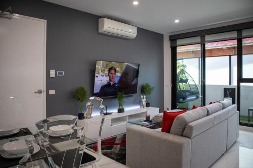 a living room with a couch and a tv on a wall at Soho 1A in Geelong