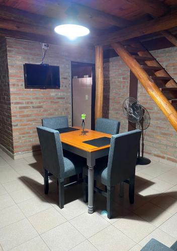 a dining room table with chairs and a tv on a brick wall at Cabañas Abigail in Nono