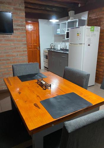 a kitchen with a wooden table with chairs and a refrigerator at Cabañas Abigail in Nono