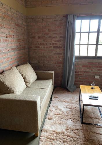 a living room with a couch and a brick wall at Cabañas Abigail in Nono