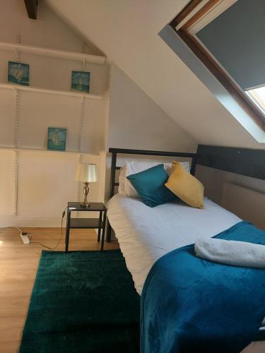 a attic bedroom with a bed with blue and yellow pillows at Hilltop Place Suites Flat Above 250 in Sheffield