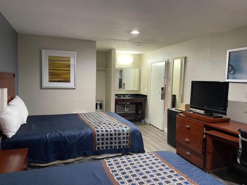 um quarto de hotel com uma cama e uma televisão de ecrã plano em Bel Air Motor Hotel em Tustin