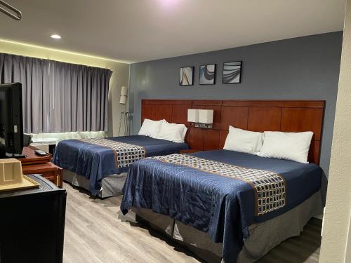 a hotel room with two beds and a television at Bel Air Motor Hotel in Tustin