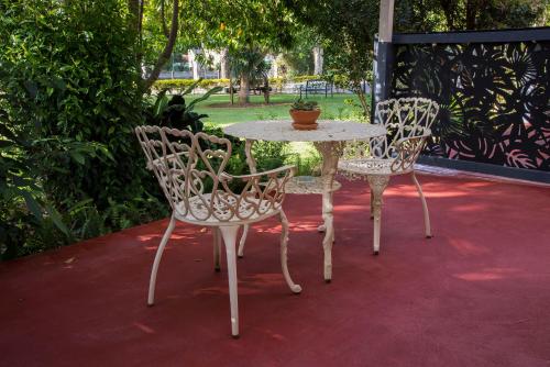 three chairs and a table with a potted plant on a patio at Maleny Hills Motel in Maleny