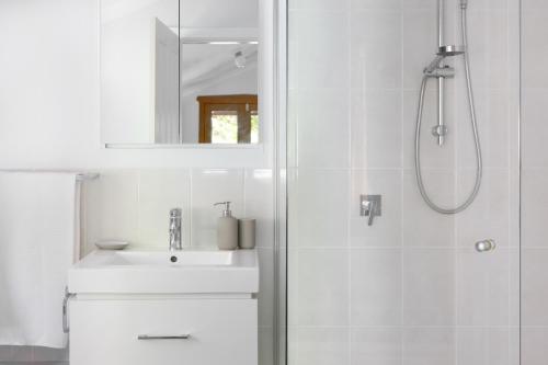 uma casa de banho branca com um lavatório e um chuveiro em Kuzman Homestead em Mudgee
